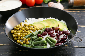 Bowl with tasty rice, beans and avocado on table