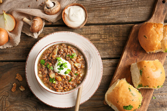 Bowl of tasty lentils soup with bread on table