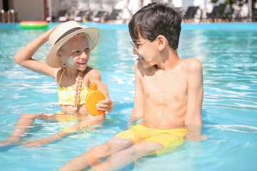 Little children with sun protection cream in swimming pool