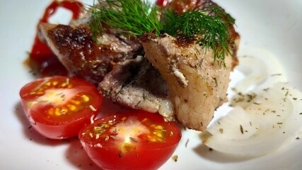 kebabs on a white plate, decorated with a sprig of dill, sliced tomato, sliced onion rings and thin strips of ketchup.