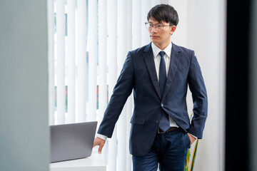 Portrait of Handsome and confident Asian Businessman with glasses showing a smile in bright modern office indoor