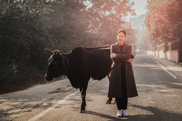 Portrait of traveller woman standing with an cow on the road.