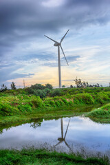 The wind turbine in the evening is reflected in the water.