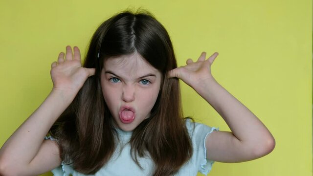 little girl grimaces in front of the camera, sticks out her tongue, teases