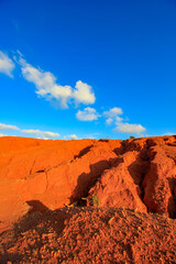 The red land is under the blue sky and white clouds.
