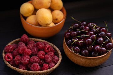 Cherry, apricots, raspberries on a wooden background