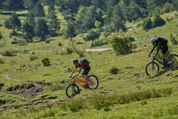 two men on a mountain bike going down a green field