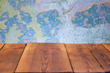 Fototapeta Pusty blat drewnianego stołu zbitego ze starych desek, w tle obdrapana wielokolorowa ściana, pomalowana farbą kredową. obraz