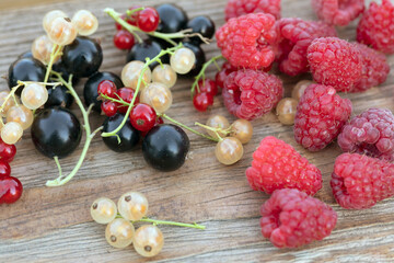 Berry fruits like strawberries, red currants, raspberries and black currants on wood background