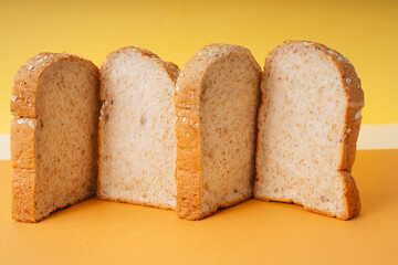 Four Home made organic sliced bread on orange yellow background.