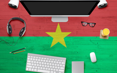 Burkina Faso flag background with headphone,computer keyboard and mouse on national office desk table.Top view with copy space.Flat Lay.