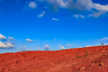 The red land is under the blue sky and white clouds.