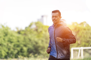 Obraz premium A man in sport hoodie jogging in the city park in the evening after stressful work. Runner jogging training and workout exercising power walking outdoors in forest city. Stock photo