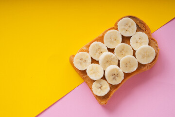 Top view - Grilled sliced bread topping with banana and jam over yellow background.