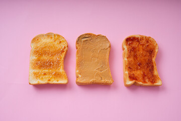 Top view - Grilled sliced bread topping with banan and jam over pink background.