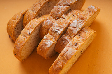 Top view - Sliced of loaf bread over orange background.