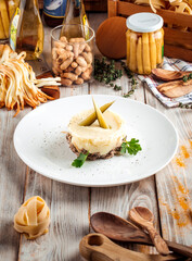 Mashed potato with beef in creamy sauce pickles