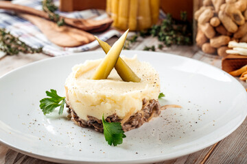 Mashed potato with beef in creamy sauce pickles