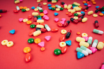 Colourful medicine pills over red background.