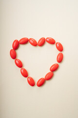 Red medicine pills in heart shape over white background.