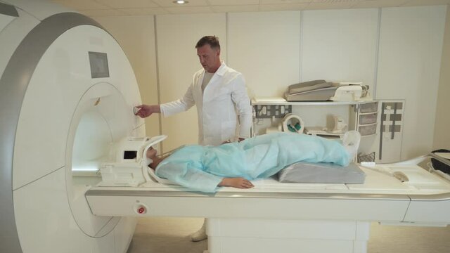 Magnetic resonance imaging, adult man doctor performs a magnetic tomographic examination of brain for young asian woman, MRI, modern technologies in medicine.