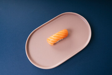 Salmon sushi on plate over blue background.