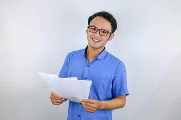 Young Asian Man is smile and happy when looking on paper document. Indonesian man wearing blue shirt.