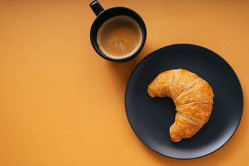 Top view close up - Golden crossiant with hot coffee over orange background.
