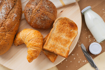Group of many type of bread on a plate and a bottle of milk. Top view.