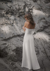 Fototapeta na wymiar girl in a white dress on nature against the backdrop of a mountain with sand