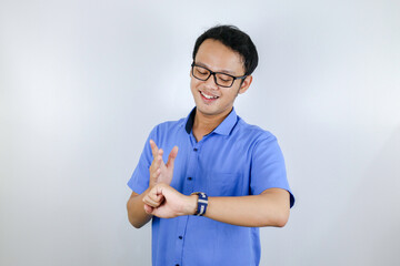 Young Asian Man wear blue shirt is happy and smiling when pointing and look into the watch isolated over white background