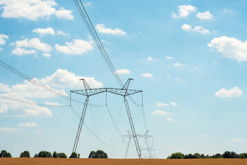 Fototapeta premium Power poles with cables stand in the field