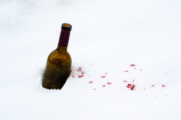 a bottle of wine in the snow red wine spilled out of it onto the snow