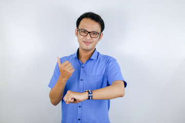 Young Asian Man wear blue shirt is happy and smiling when pointing and look into the watch isolated over white background