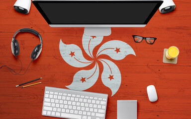 Hong Kong flag background with headphone,computer keyboard and mouse on national office desk table.Top view with copy space.Flat Lay.