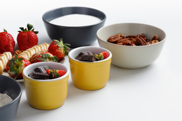 Ingredients for brownies/chocolate muffins/chocolate cupcakes: flower, sugar, chocolate, pecans, banana and strawberries