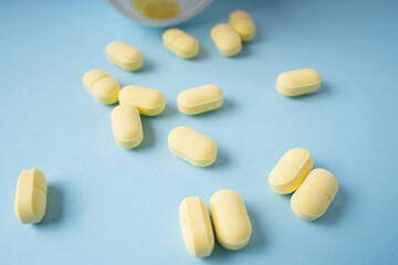 Fototapeta na wymiar Yellow pills and white bottle over blue background.
