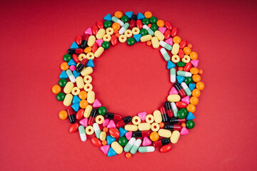 Colourful medicine in circle shape over red background.