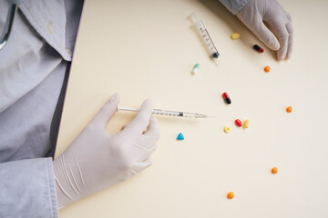 Doctor wearing plastic gloves using syringe and medicine pills.