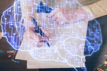 Double exposure of writing hand on background with brain hologram. Concept of learning.