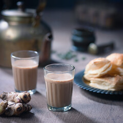 Indian Masala Cutting Chai being poured into a glass. Served with Khari Biscuits.