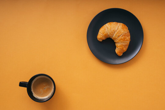 Top view close up - Golden crossiant with hot coffee over orange background.