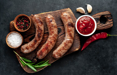 grilled sausages with spices and rosemary on a stone background