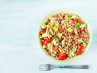 Fresh Italian farro spelt salad with tomatoes, avocado and cucumbers on wooden turquoise board. Easy recipe whole food meal