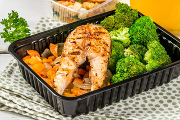 A piece of fried fish with broccoli in a container