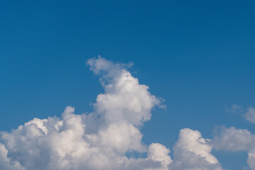 Naklejka na ściany i meble Dense billowing cloud on a background of blue sky