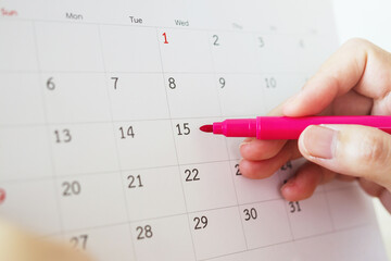 Hand with pen writing on calendar date