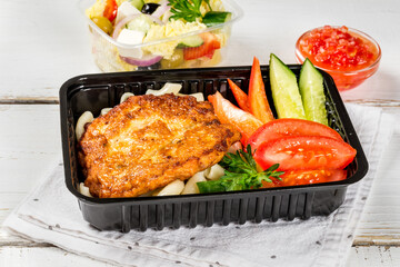 Cutlet with pasta, vegetables in a black container
