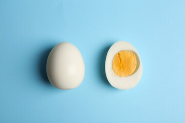 Fresh hard boiled chicken eggs on light blue background, flat lay