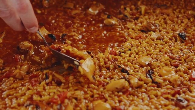 Detail shot of a paella and how they take a tablespoon